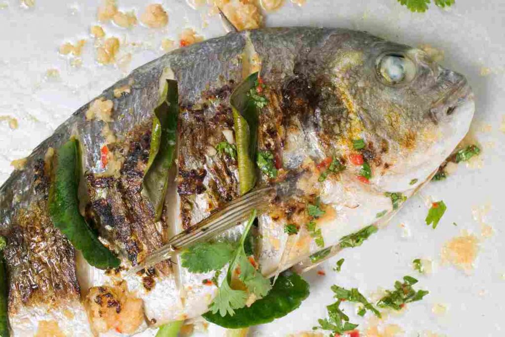 Orata al limone in un piatto guarnita con prezzemolo per la cena a dieta