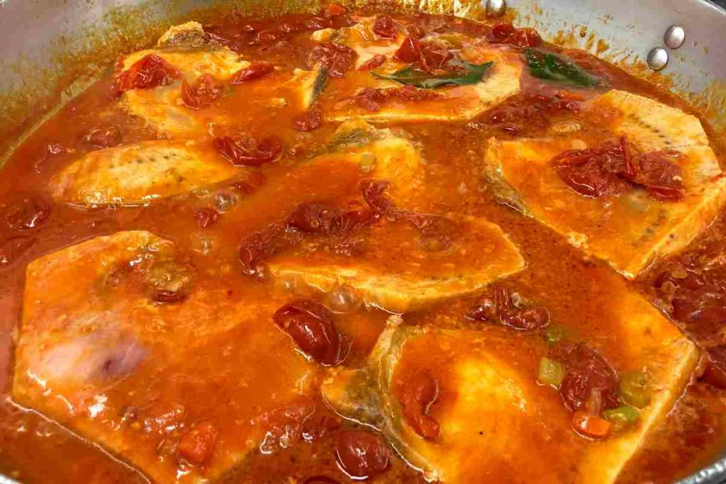 Fette di pesce spada in umido al sugo in una grande padella