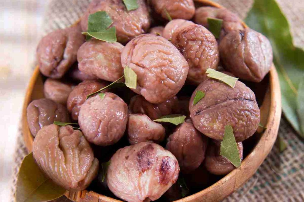 Castagne bollite con foglie di alloro in una ciotola di legno