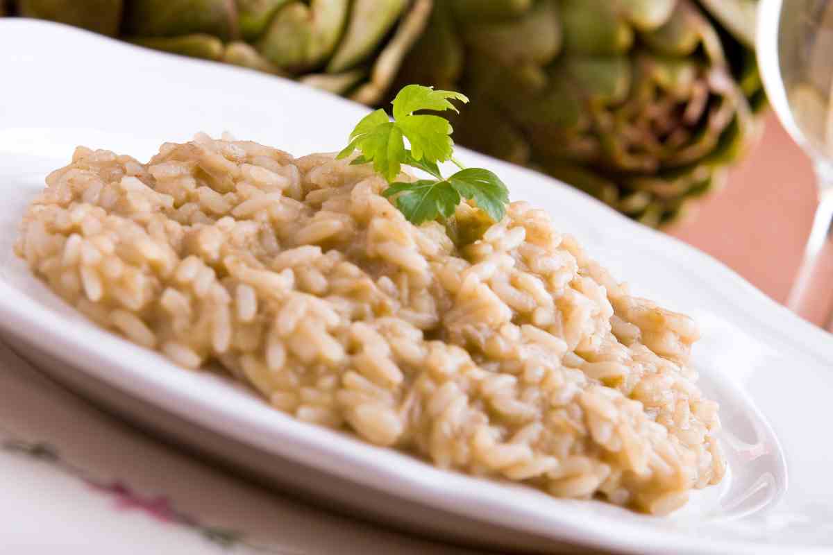 Risotto ai carciofi in un piatto con dietro ortaggi