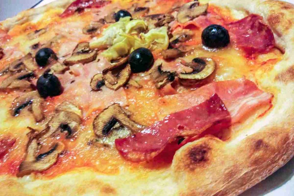 Pizza capricciosa con funghi olive carciofi e prosciutto