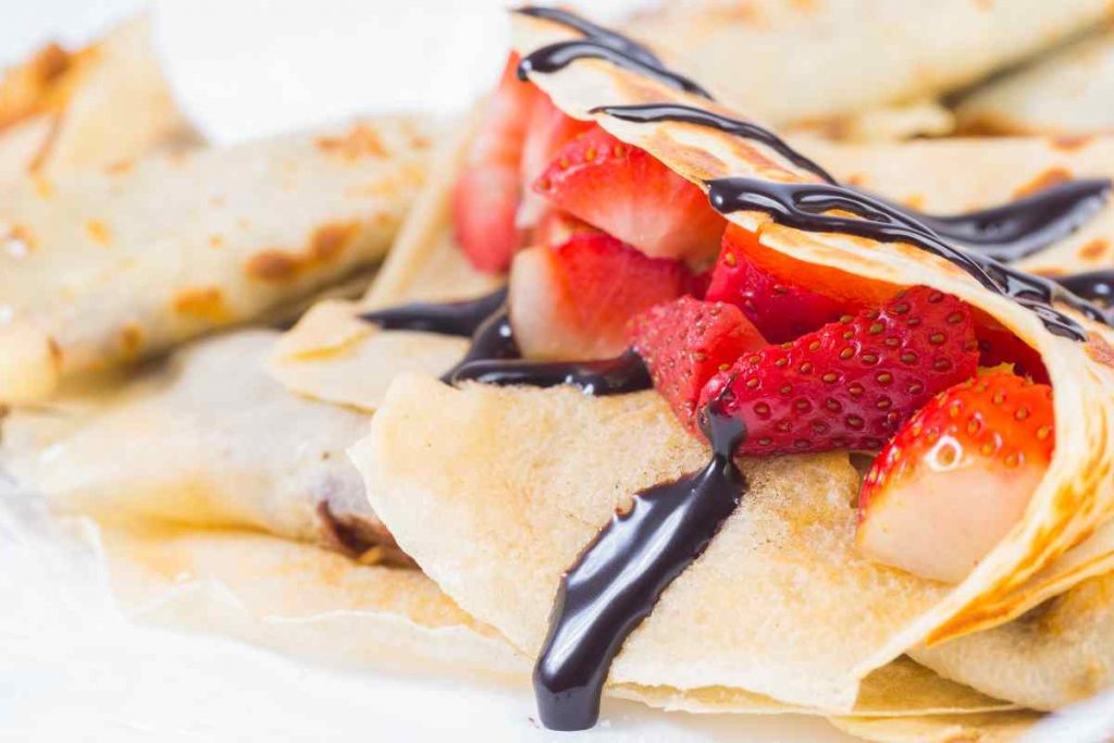 Crepes senza burro farcite con fragole a pezzi e topping di cioccolato