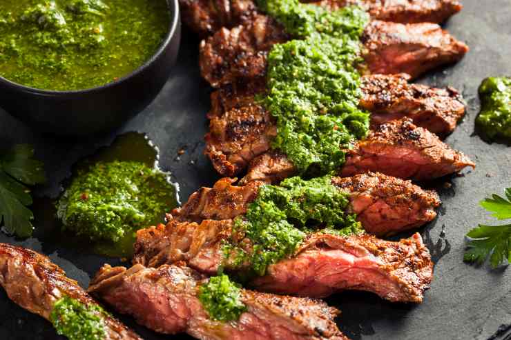 Salsa verde su tranci di arrosto a fette su vassoio di ardesia