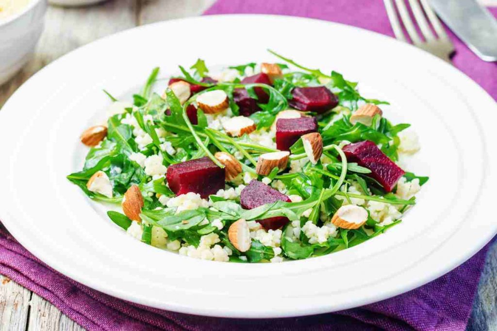 Carpaccio di barbabietole rosse, rucola, noci e parmigiano su un piatto