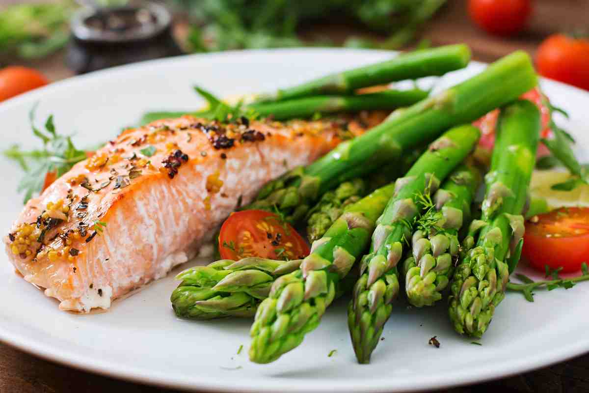 piatto con trancio di salmone e asparagi lessati con qualche pomodorino di contorno