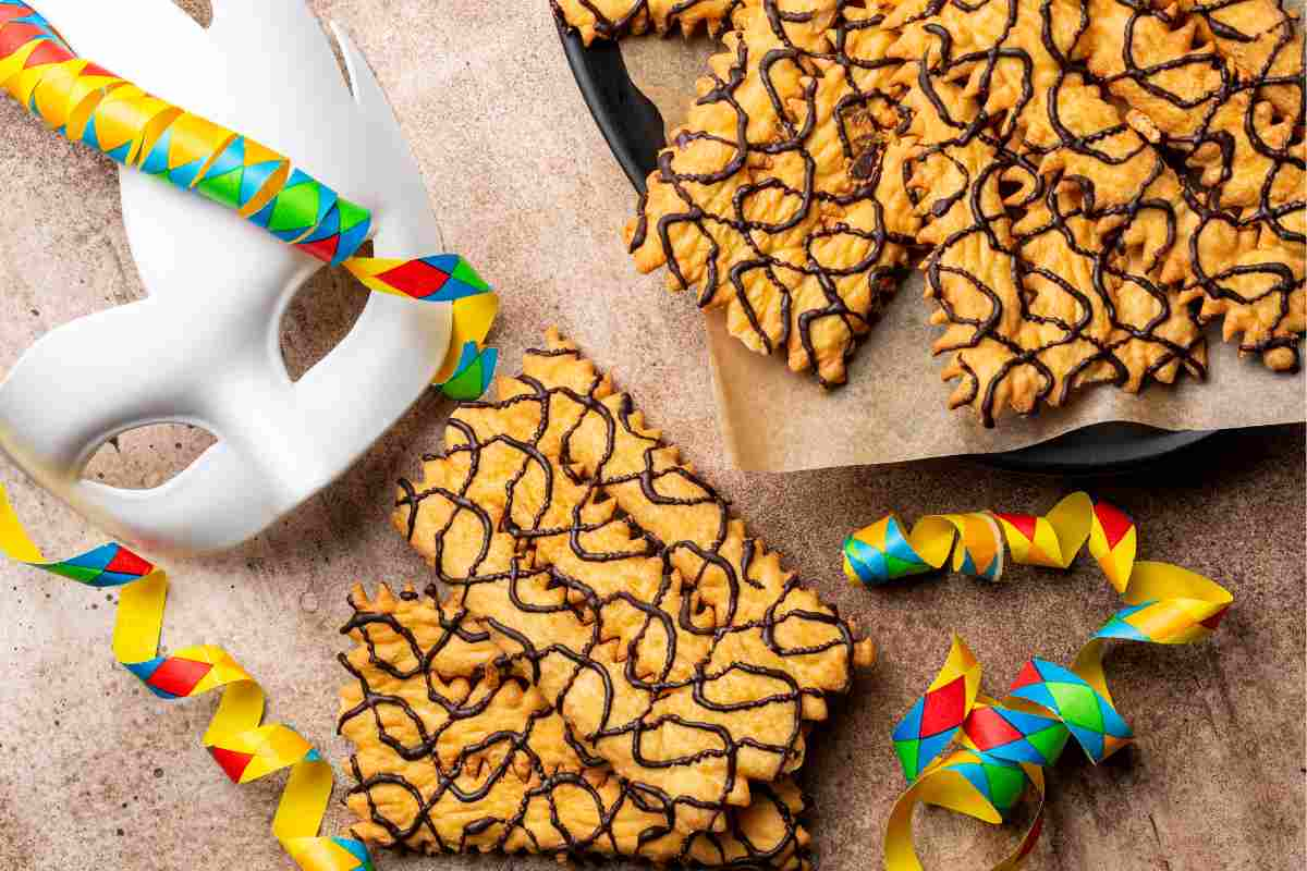 Maschera di Carnevale bianca con chiacchiere al cioccolato, uno dei dolci del menu di Carnevale