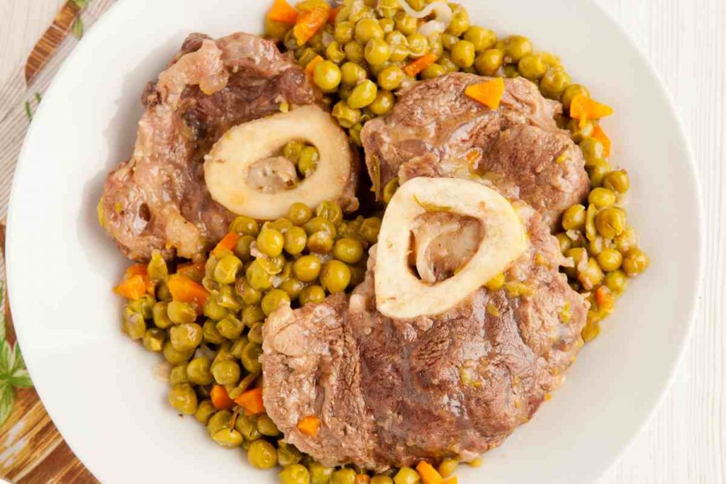 Ossobuco con i piselli in un piatto visto dall'alto