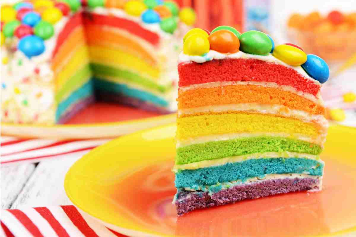 Torta arcobaleno tagliata a fette decorata con smarties