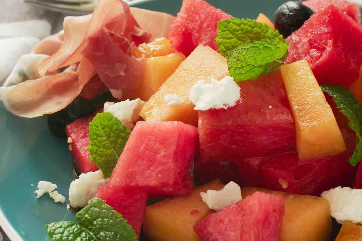 ricette estive veloci e sfiziose, un piatto con insalata di anguria, mango e prosciutto crudo