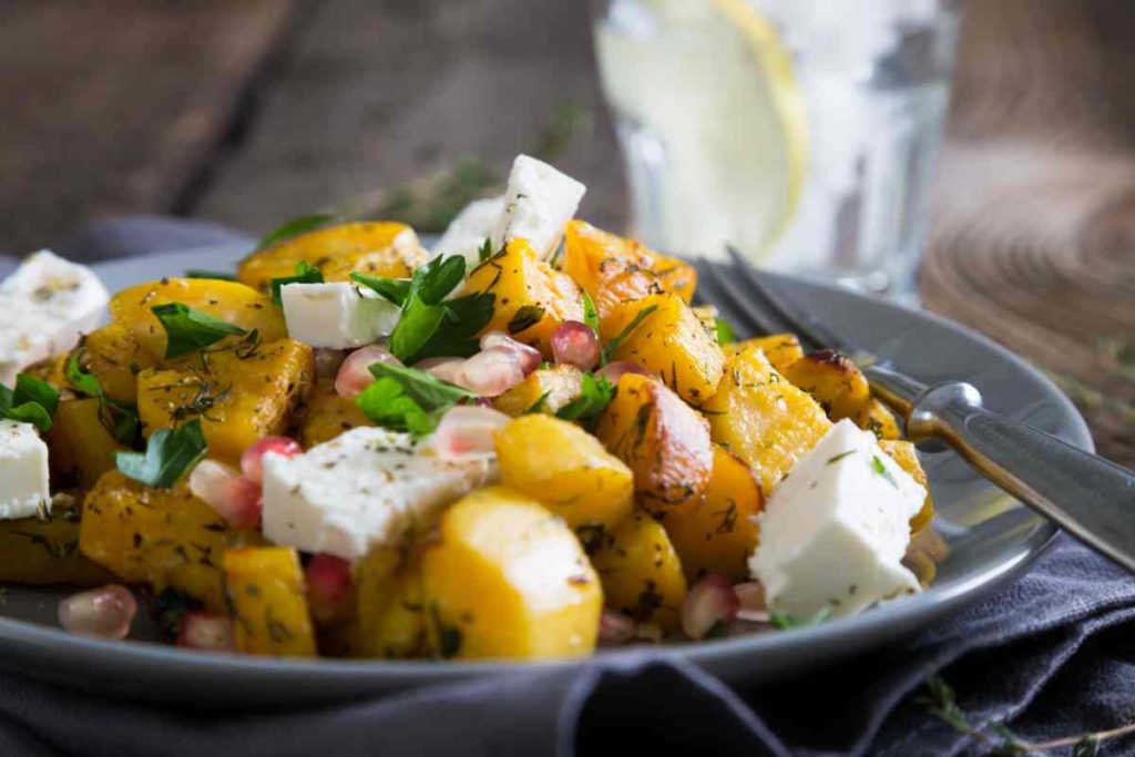 Insalata di patate con feta e gamberetti guarnita con chicchi di melograno