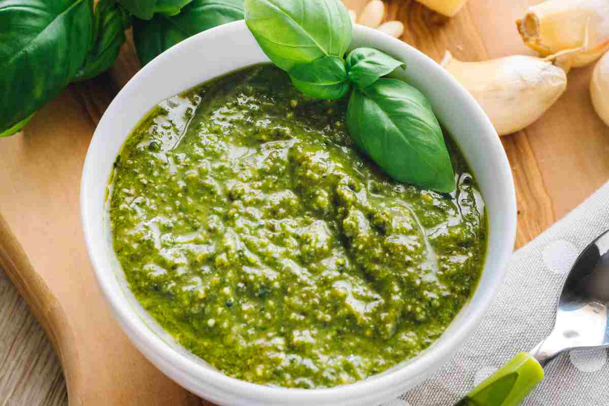 Pesto alla genovese in una ciotola preparato con la ricetta tradizionale originale con intorno aglio basilico pinoli e mortaio