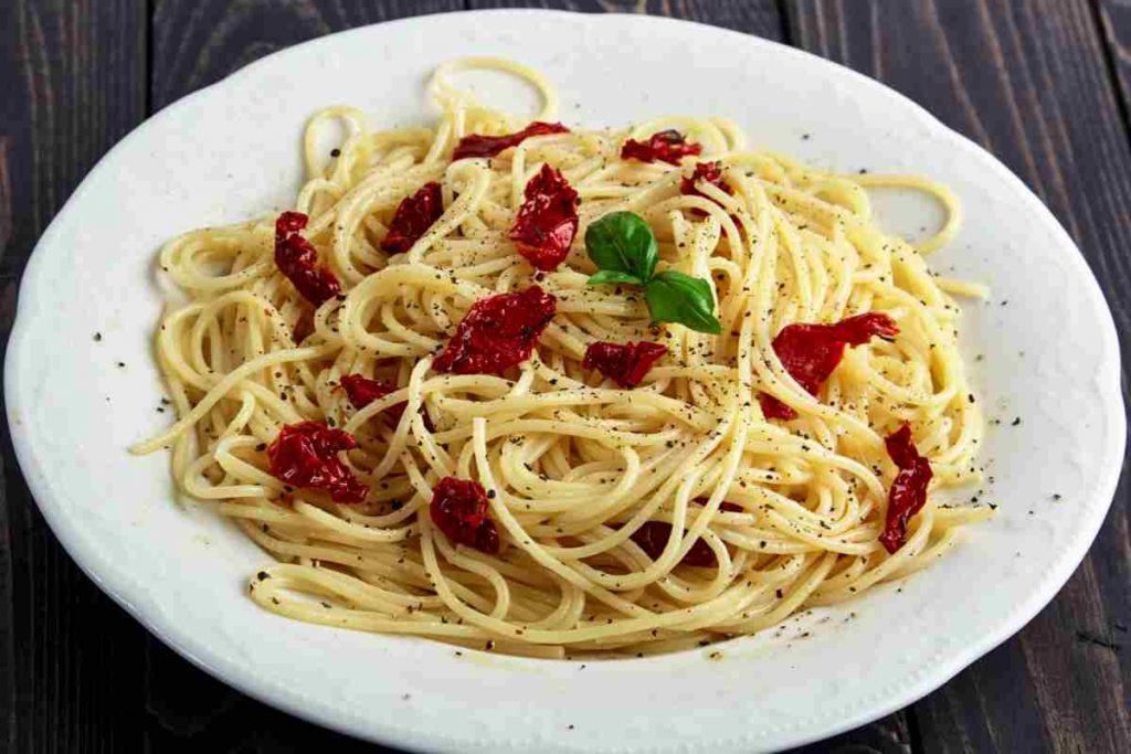 Spaghetti con pomodori secchi su un piatto bianco