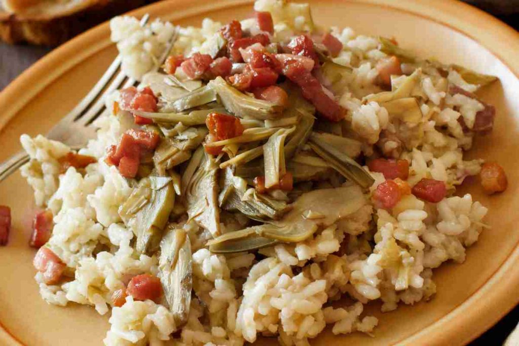 Risotto con carciofi e pancetta in un piatto piano