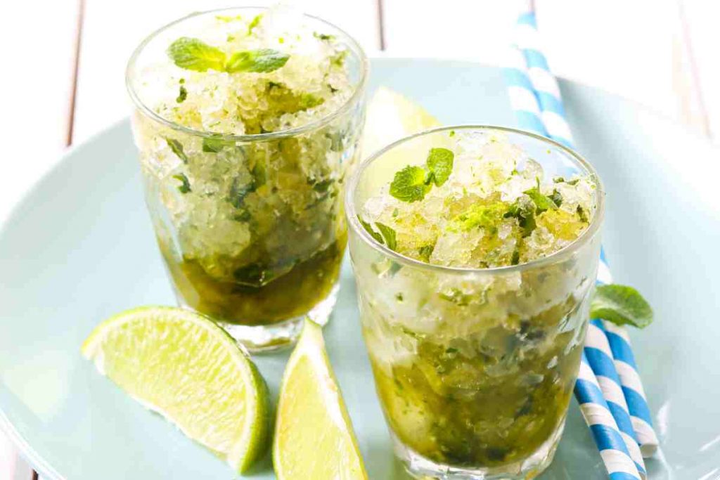 Granita al Mojito in due bicchieri con cannucce colorate e spicchi di lime