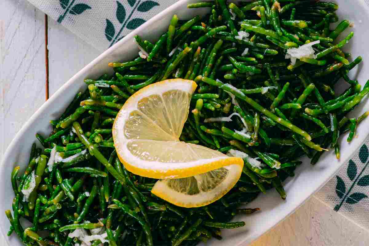 Insalata di Salicornia in un vassoio ovale bianco e una fettina di limone sopra