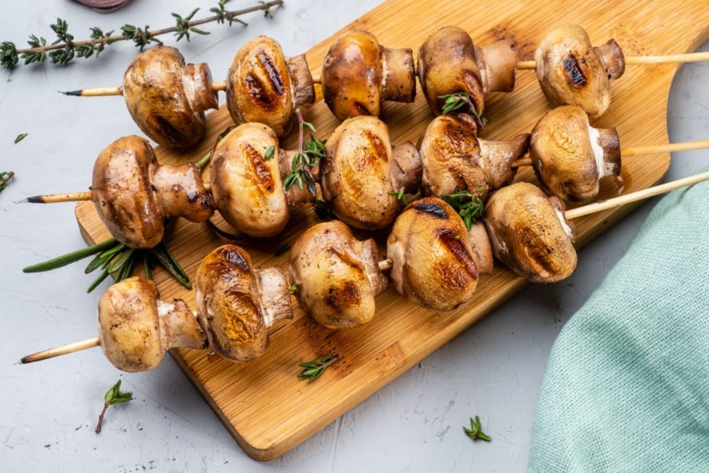 spiedini di funghi su tagliere di legno