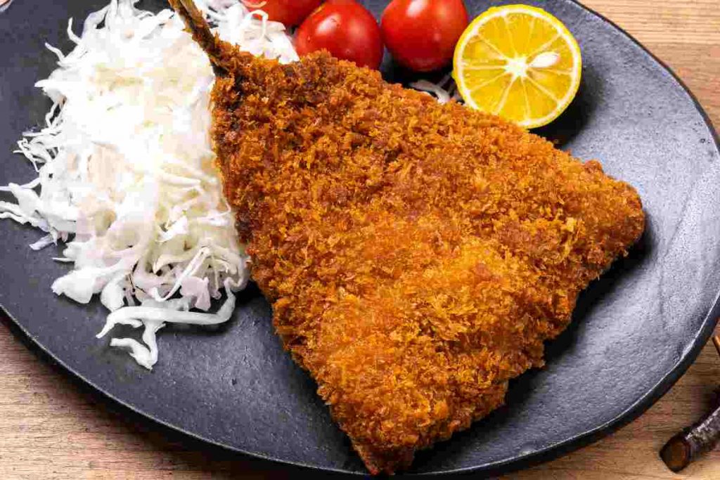 Cotoletta di sgombro fritta su un piatto nero