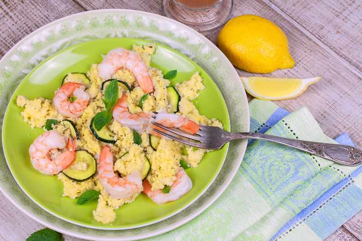 Vista dall'alto di un piatto pieno di cous cous con zucchine e gamberetti 