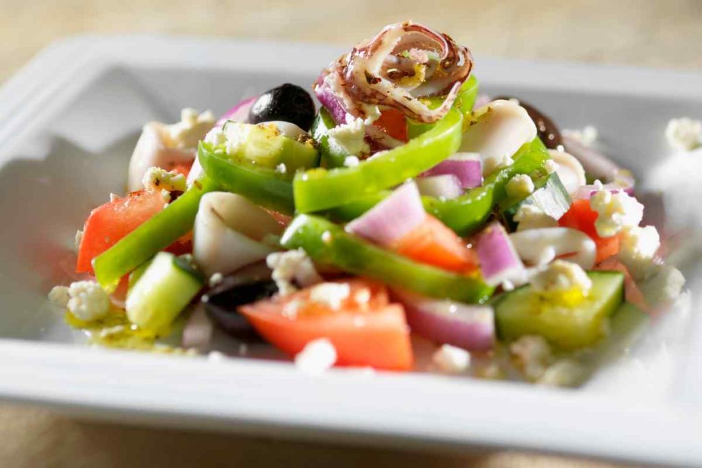 Insalata di calamari con verdure in un piatto quadrato