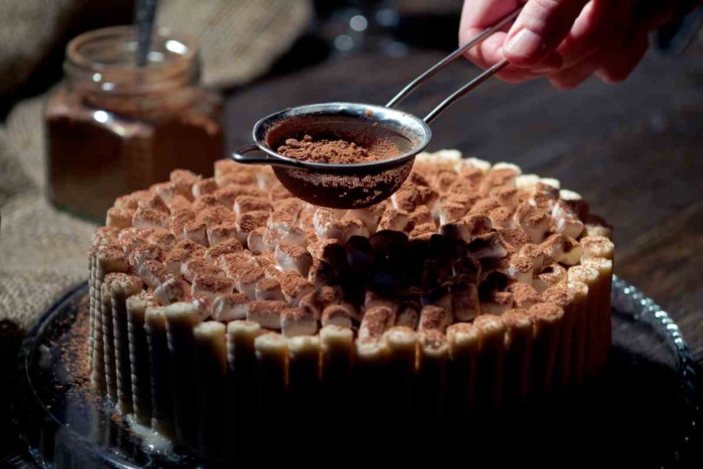 Torta fredda con wafer mentre viene spolverata con cacao