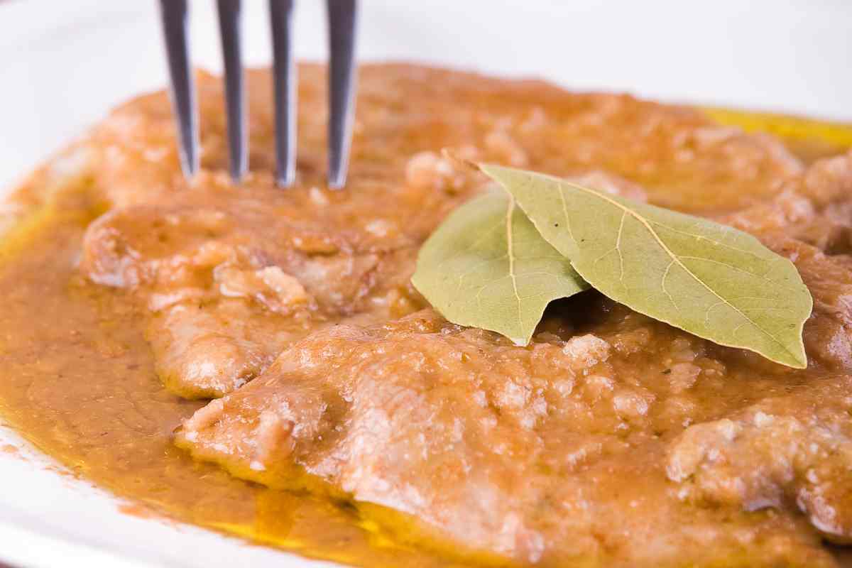 Scaloppine al Marsala con una foglia di alloro in un piatto bianco