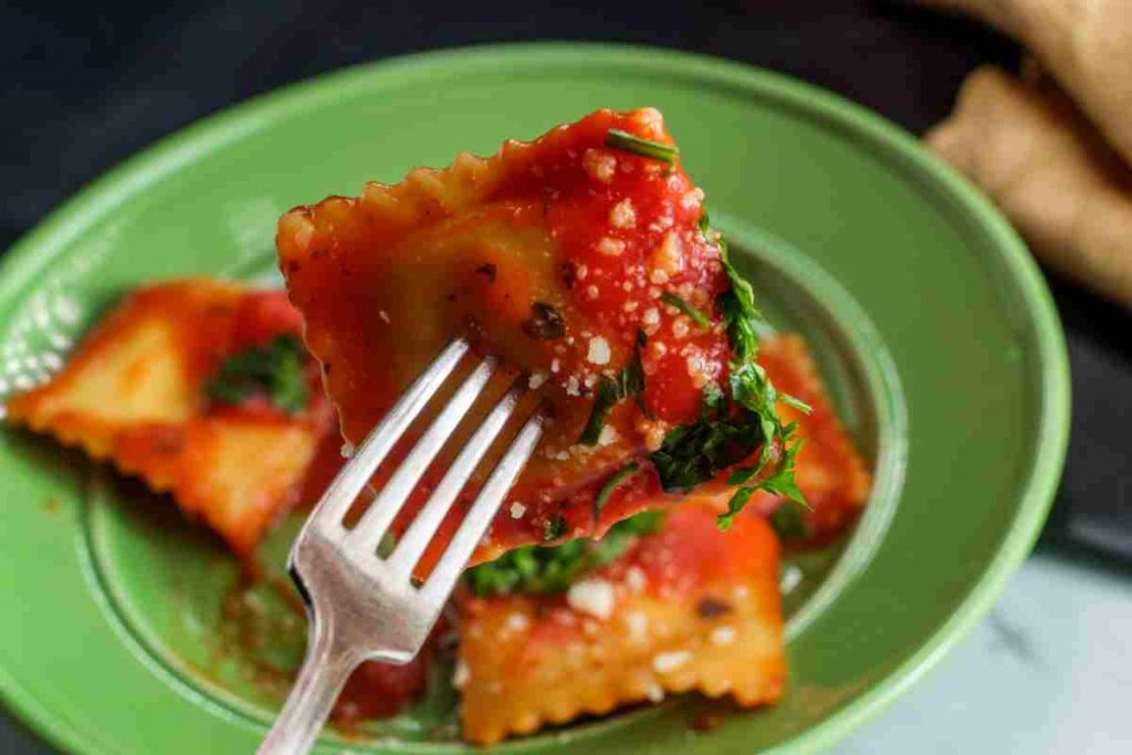 Tortelli alla marinara con sugo all'origano sulla punta di una forchetta