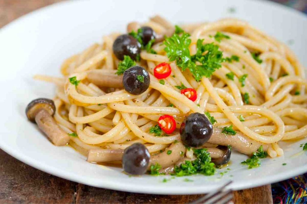 Pasta tipo spaghetti ai funghi pioppini in un piatto bianco