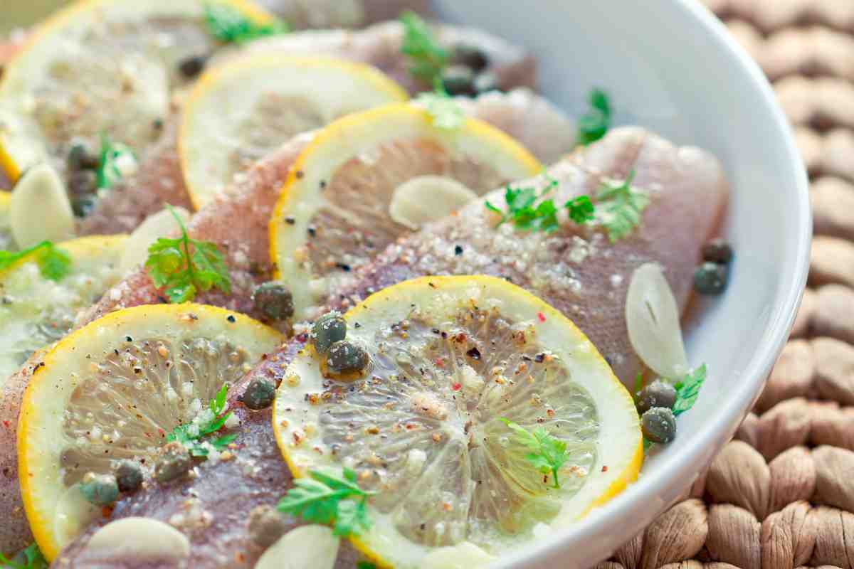 Sogliola ai capperi in una ciotola guarnita con limone e prezzemolo