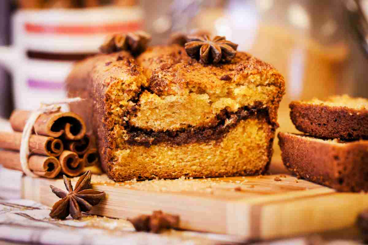 Plumcake alla cannella tagliato a metà su un vassoio di legno