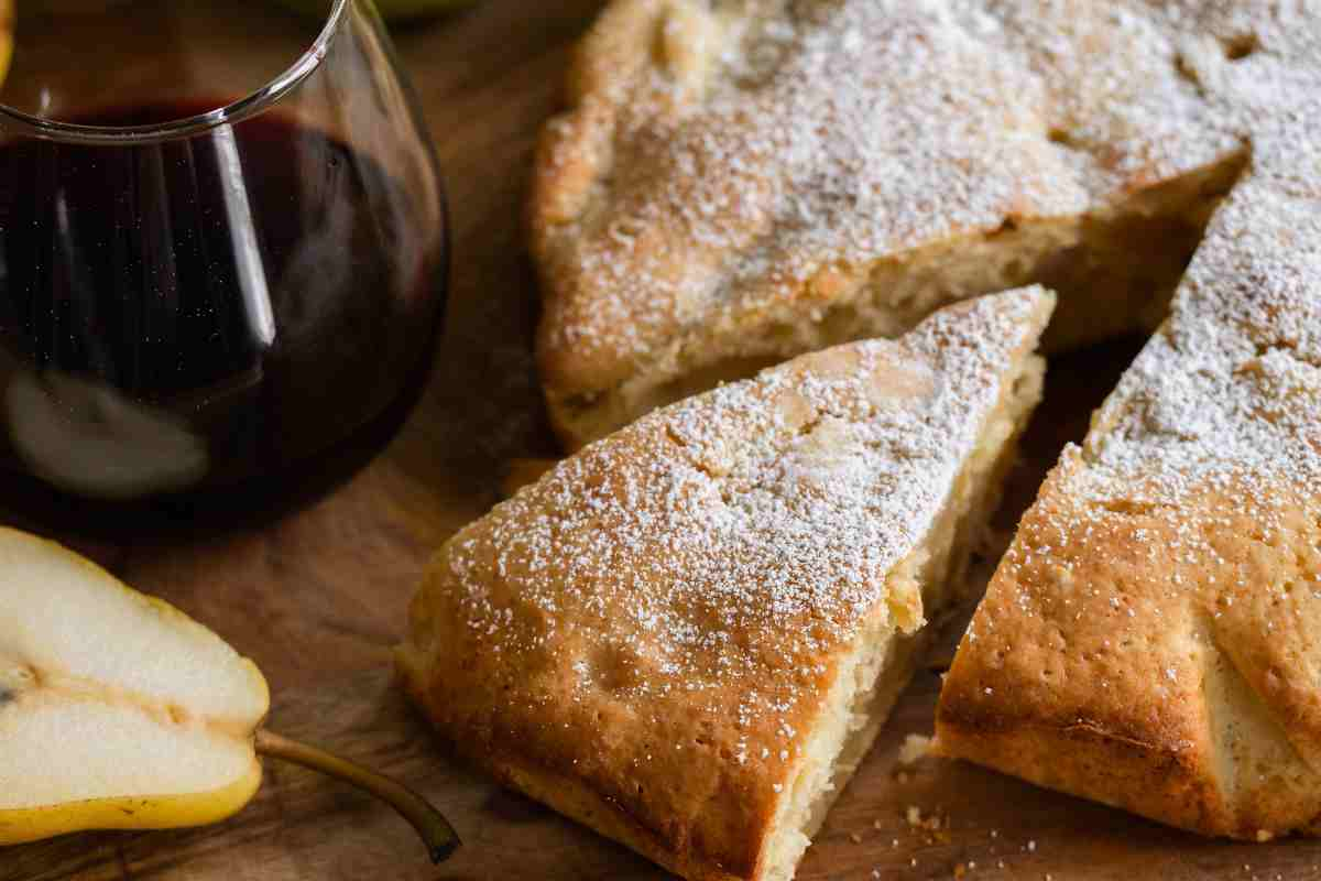 Torta alle pere tagliata a spicchi con vicino un frutto