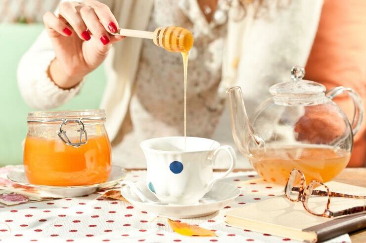 Tavolo colazione, donna aggiunge miele nella tazza