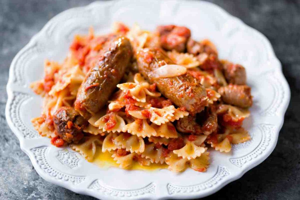 Farfalle con il sugo di salsiccia in un piatto bianco