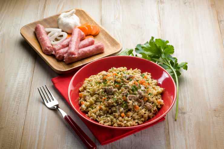 Risotto con porri e salsiccia con ingredienti sullo sfondo