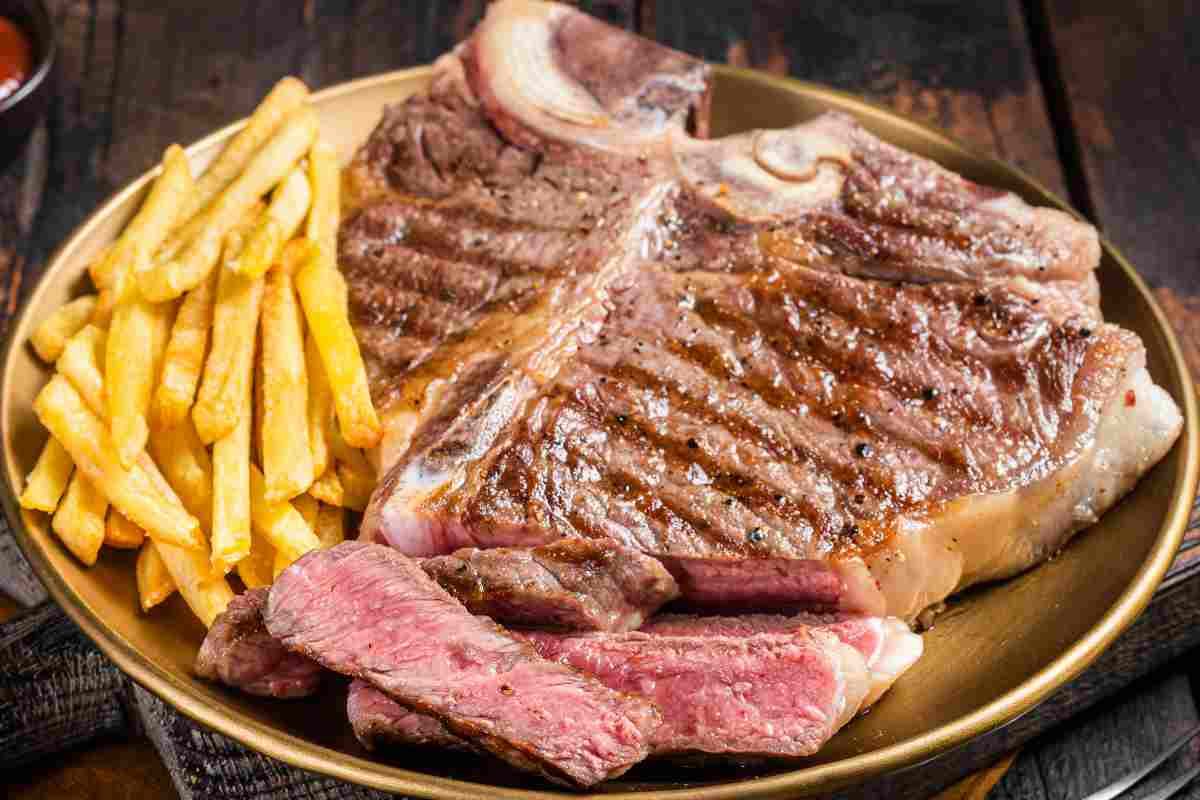 Bistecca alla fiorentina in un piatto con patatine fritte