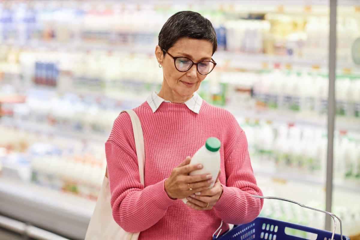 Donna che consulta le informazioni di una bottiglia di latte