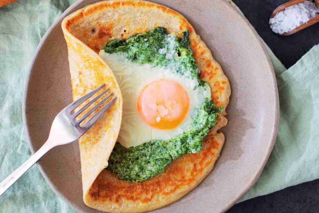 Crepes con spinaci e uova in un piatto visto dall'alto