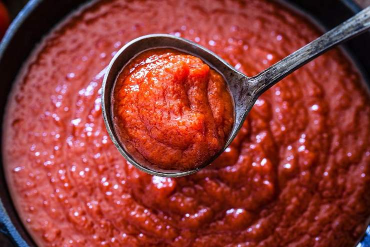 passata di pomodoro in padella con mestolo pieno