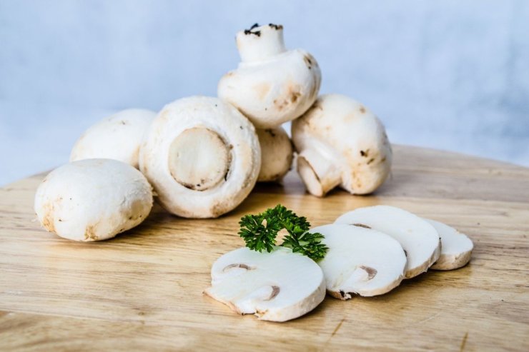 funghi champignon interi e tagliati su tagliere