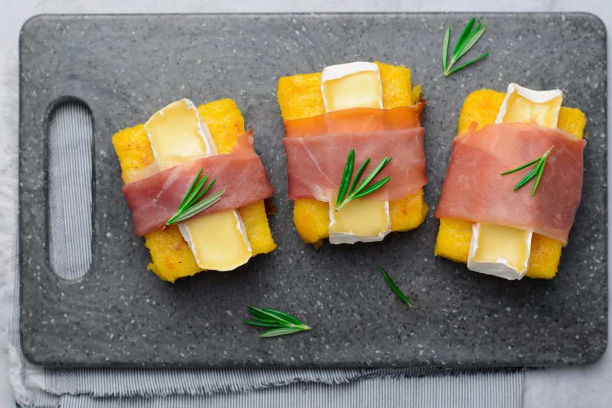 I crostini di polenta farciti con speck e brie diventeranno il tuo antipasto preferito