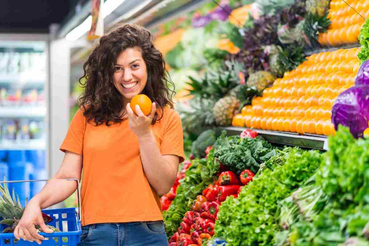 donna al supermercato con arancia