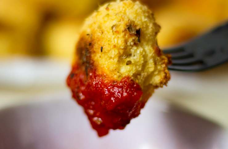 pallina di ricotta fritta su forchetta immersa in salsa rossa