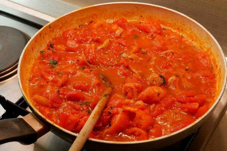 padella con sugo di pomodoro e mestolo di legno