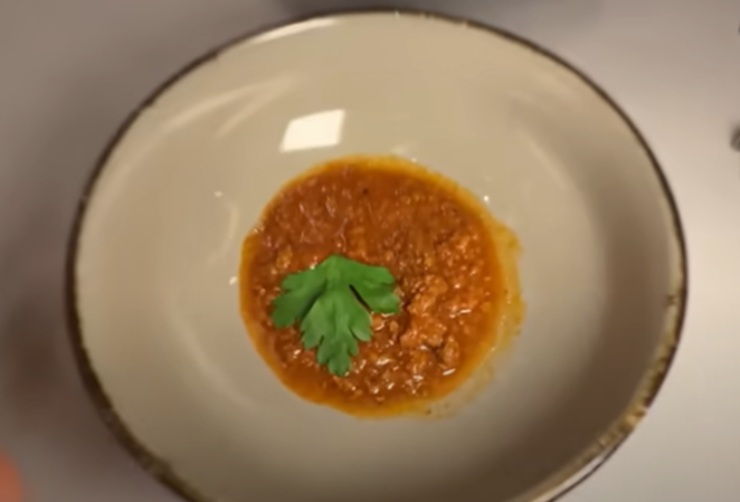 ragu di carne dentro ad un piatto bianco con sopra una foglia di prezzemolo