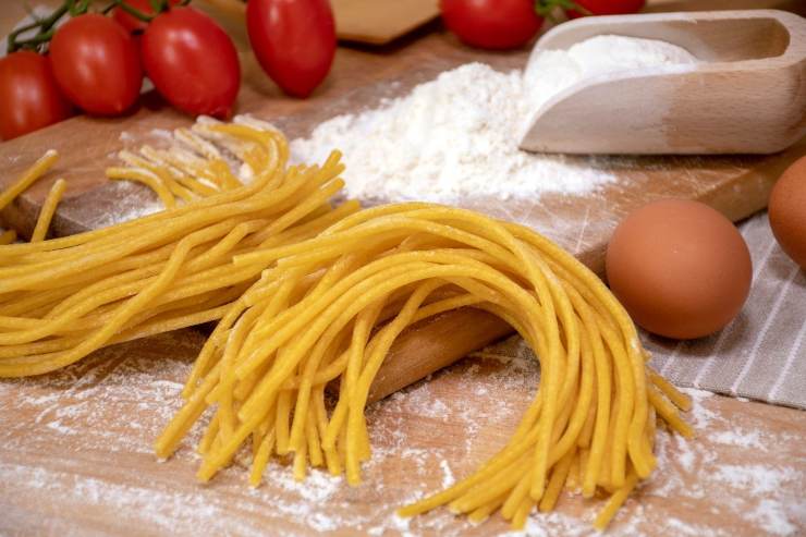 bigoli freschi su tagliere con uova, pomodorini, farina