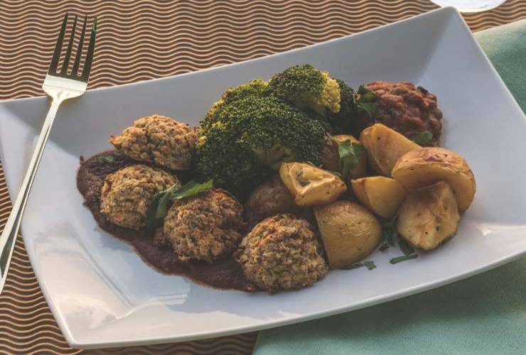 piatto con polpette, broccoli e patate e accanto una forchetta