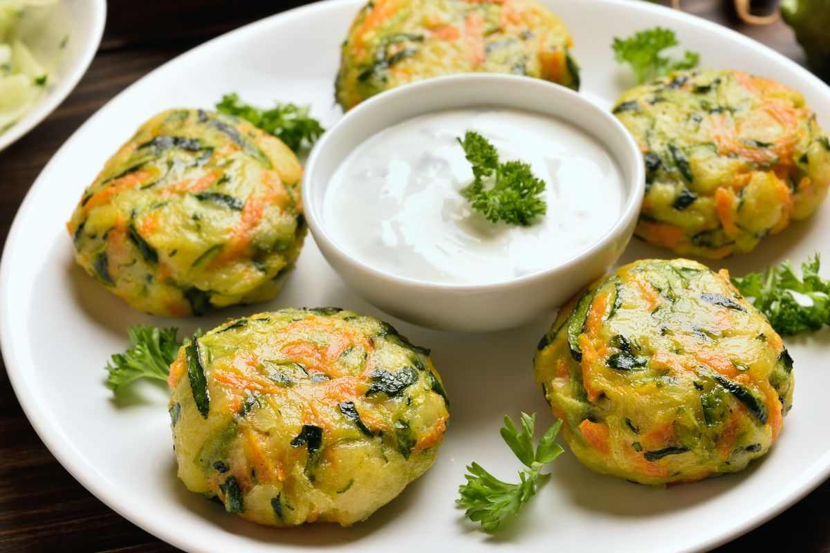 frittelle carote e zucchine su piatto bianco con salsa allo yogurt