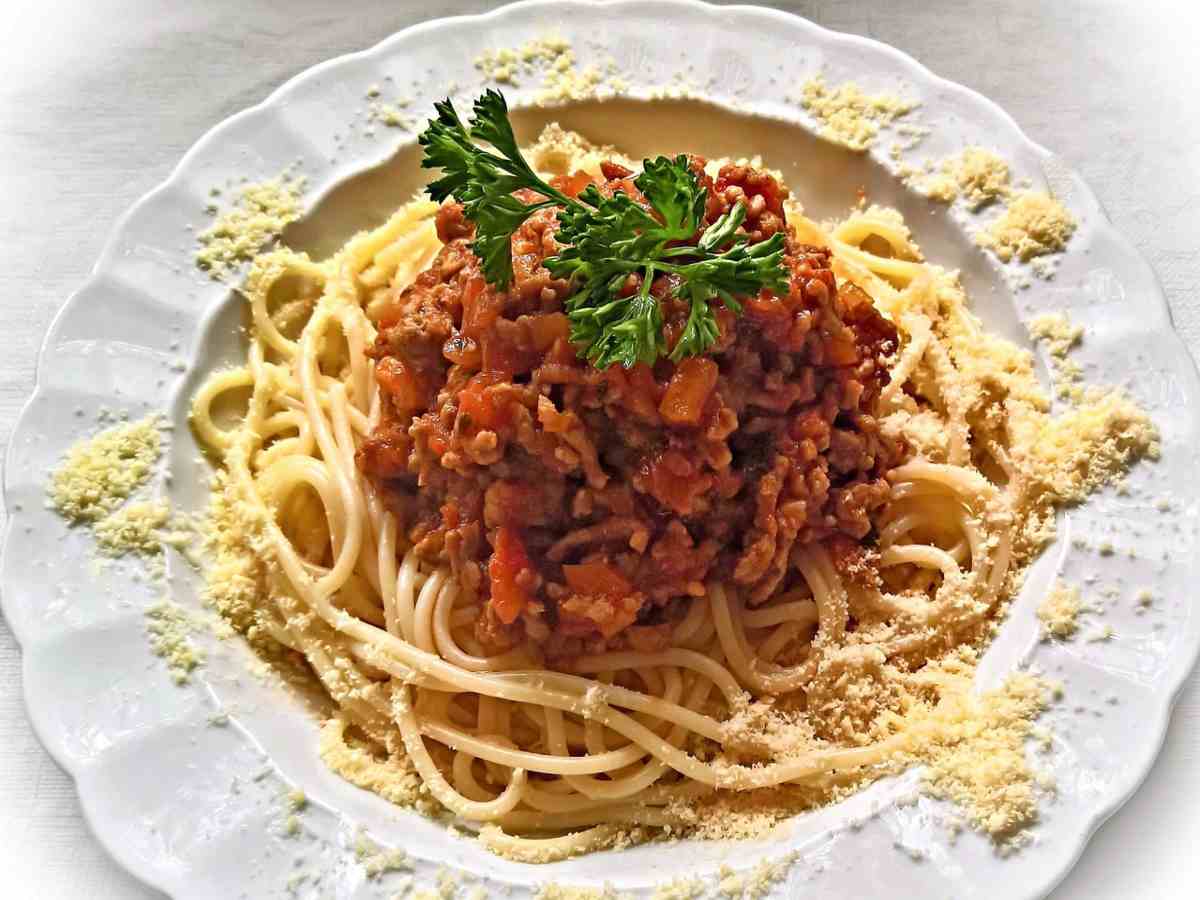 piatto di spaghetti con ragù formaggio grattugiato e un ciuffo di prezzemolo sopra