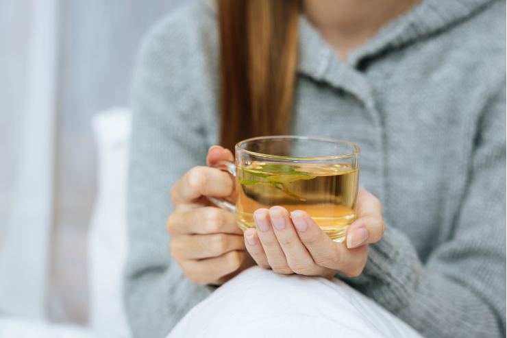 Persona con tazza di tisana in mano