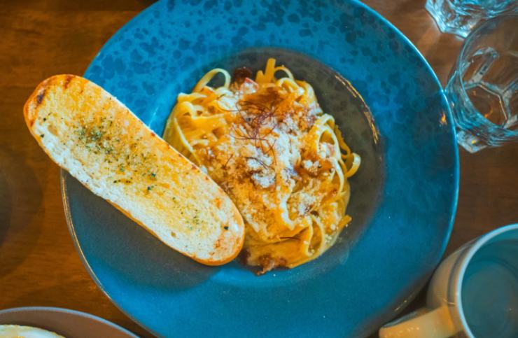 piatto blu con pasta cremosa e pane tostato